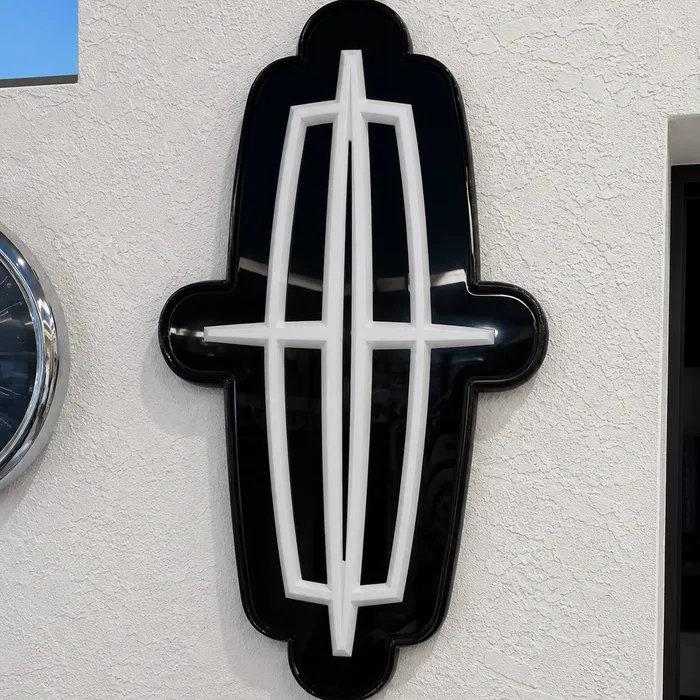 A black and white Lincoln emblem in glossy epoxy on a textured white wall